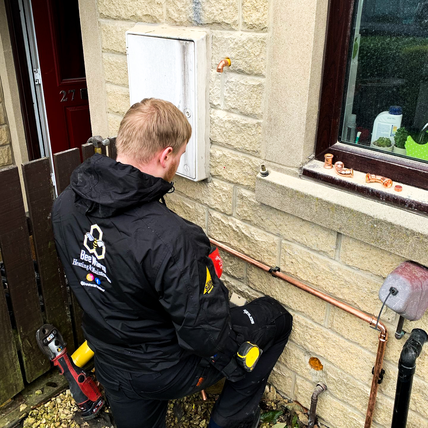 A Bee Warm engineer beside a newly installed wall-mounted air conditioning unit